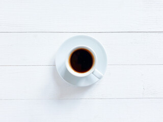 Top view of white cup of black coffee or hot chocolate on a shabby white board wooden table. Flat lay lifestyle, copy space. Good morning concept.