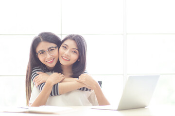 Obraz premium Portrait smiling young asian lesbian couple hugging each other while sitting together on work at home time. LGBT Lesbian couple love moment.