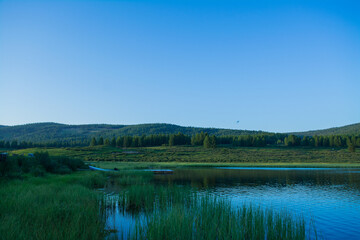 A beautiful mountain lake with reeds surrounded by mountain ranges and impenetrable forests. The lake is high in the Altai mountains