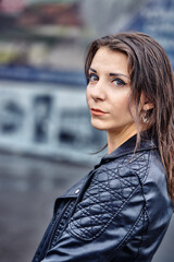 Portrait of a beautiful brunette girl in a black leather jacket on a cloudy summer evening. Close-up.
