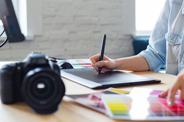 Close up portrait of graphic designer hands retouching images using graphic drawing tablet in...