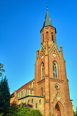Fototapeta na wymiar The tower of the historic, neo-Gothic red brick church in the village of Sokola Dabrowa