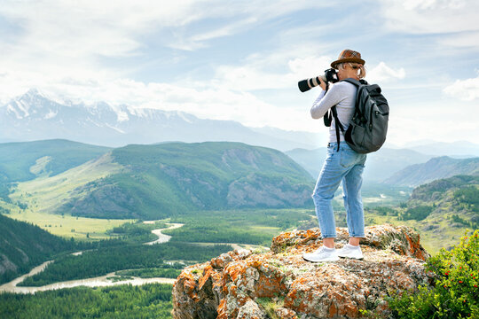Woman photographer taking photo at mountain peak. Hiker in the mountains.