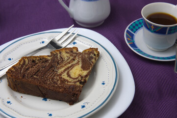 Portion of zebra cake next to a cup of coffee