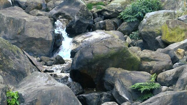 Close footage of waterfall passing through rocks and green vegetation. Footage shot at Jhalong, Dooars, West Bengal - India.