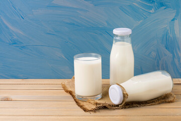 Rustic milk bottle and milk glass placed on a wooden table on a blue background Organic milk products that are delicious nutritious and healthy