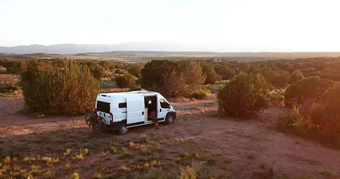 Aerial footage of a white converted camper van on the edge of a long mountain ridge overlooking the valley below.