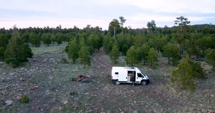 Aerial footage of a white converted camper van on the edge of a long mountain ridge overlooking the valley below.