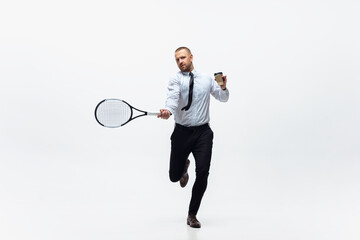 Time for movement. Man in office clothes plays tennis isolated on white studio background. Businessman training in motion, action. Unusual look for sportsman, new activity. Sport, healthy lifestyle.