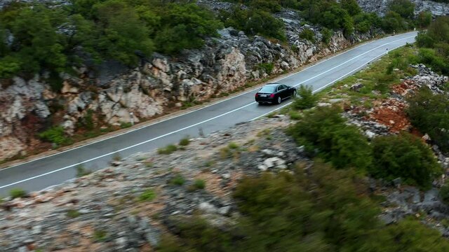 Tracking aerial shot as car driving through scenic mountain road in Croatia