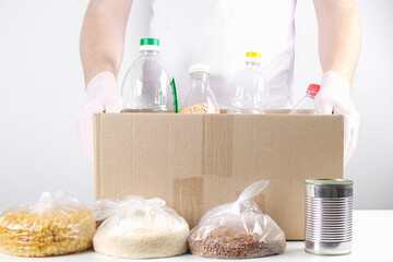 Obraz na płótnie Canvas Volunteers with donation box with foodstuffs on grey background.