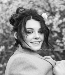 a brunette with a flower in her hair smiles in a man's jacket draped over her shoulders