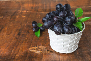 .Black grapes in a basket on a wooden table