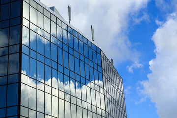 Fototapeta na wymiar Clouds reflected in the mirror-glass windows of a modern office building