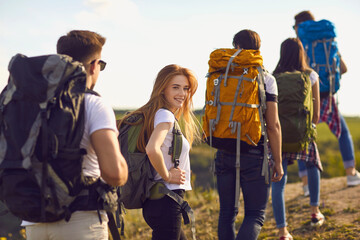 A group of young hikers are walking on hill in nature.