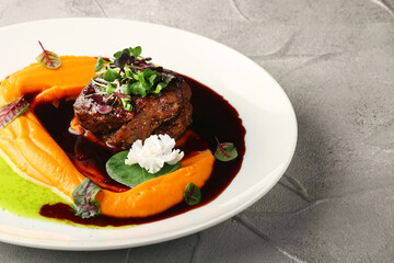 filet mignon with mashed pumpkin and microgreen in white plate on concrete background