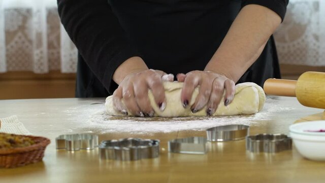 Close-up women's hands sprinkles dough with flour and kneads hands baking pastry at home, preparing pie cake or danish cookies. DIY bakery, baking moulds and rolling pin on table sprinkled with flour