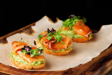 Selection of tasty bruschetta or canapes with salmon closeup. salmon tapas with guacamole and topped microgreen