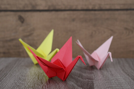 Folding origami cranes on wooden