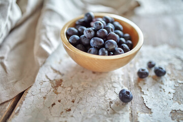 Image of blueberries in wooden bowl on rustic village table.