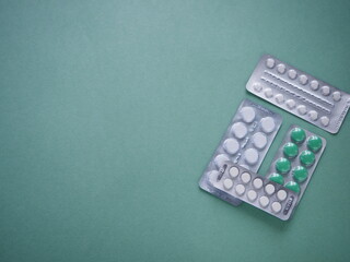 Medicines, blisters of pills close up on a green background, coronavirus infection