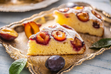 Homemade plum cake in vintage plate on wooden table. Plums pie with sugar powder