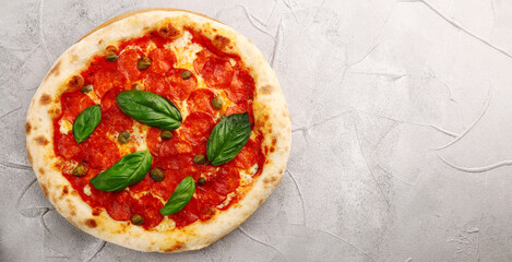 pepperoni pizza with capers and basil closeup on light concrete or stone table or background
