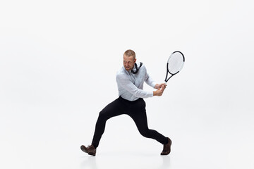 Time for movement. Man in office clothes plays tennis isolated on white studio background. Businessman training in motion, action. Unusual look for sportsman, new activity. Sport, healthy lifestyle.