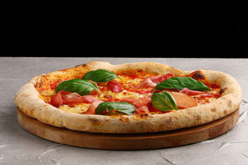 pizza prosciutto with basil and Mozzarella closeup on light concrete or stone background
