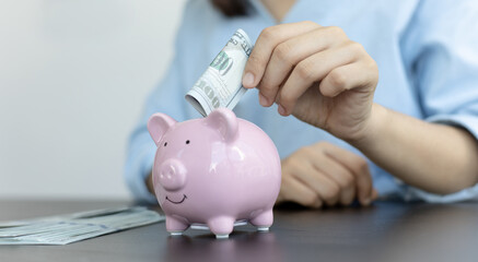 Businessman's hand holds the money in the piggy bank for saving money for future use, saving money for finance accounting concept.