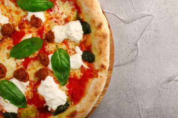 strachatella pizza closeup on light concrete or stone background. pizza with meat, pesto, tomatoes and stracciatella cheese top view