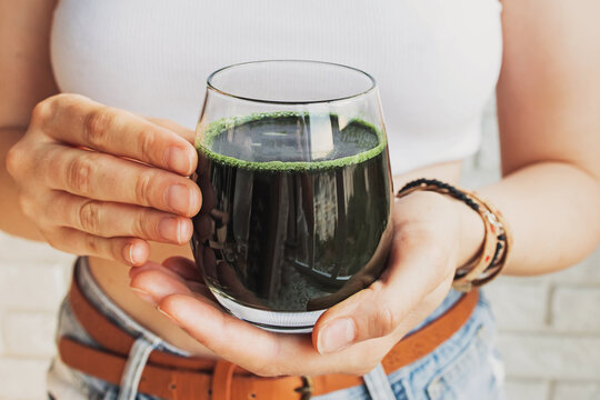Woman holding glass with healthy spirulina drink close-up