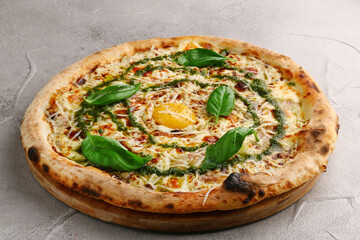 carbonara pizza with tomatoes, pesto, basil, mozzarella, parmesan and egg close up on gray concrete or stone table