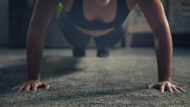 Detail of woman exercising on the floor at home.Woman doing push-ups at home. Woman fitness training on the ground. Industrial style house
