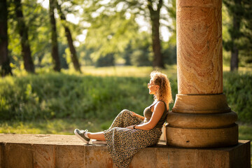 Young woman with sunglasses sitting in park on sunny day