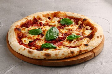 pizza with dried tomatoes, chicken, basil, tomatoes and mozzarella cheese close up on gray concrete or stone table top view
