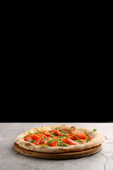 salmon pizza with green close up on gray concrete or stone table and black background for copy space