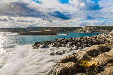 Waves smothering the rocks as clouds fill the sky
