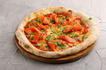 salmon pizza with green close up on gray concrete or stone table top view.
