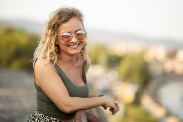 Beautiful smiling woman standing  on fortress fence and enjoying the view