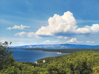 Hvar island, aerial cloudscape of coastline forest, Adriatic sea and a passenger ferry boat.