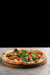 salmon pizza with spinach close up on gray concrete or stone table and black background for copy space. seafood italian pizza