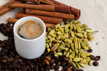 Cup of coffee with roasted beans, seeds and cinnamon