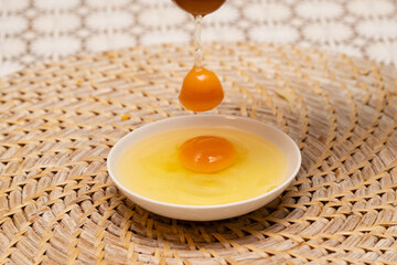 白い小皿に落ちる生卵