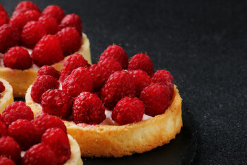 Fruit raspberry tart cakes on a black tabe. mini tart pie with berries