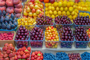 Assortment of fresh berries and fruits at the farmers market with fruits and vegetables, open shelves, display cases. Healthy natural products. Autumn harvest