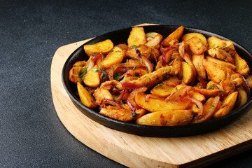 frying pan with potatoes meat and roast onion on black concrete background. mexican food concept. potatoes fried in a pan