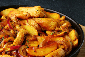 frying pan with potatoes meat and roast onion on black concrete background. mexican food concept. potatoes fried in a pan