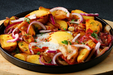 frying pan with potatoes meat and egg on black concrete background. mexican food concept. potatoes fried in a pan