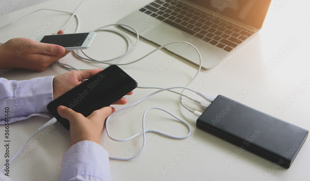 Poster two people using two mobile phone sharing usb power bank on a table to charge the mobile devices.tec